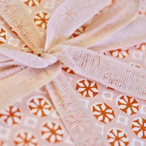 A parcel wrapped with Blush ribbon and Sea Urchin Neon paper by Cambridge Imprint