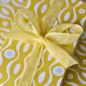 A parcel wrapped with Lemon ribbon and Persephone Mustard paper by Cambridge Imprint