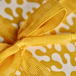 A parcel wrapped with Marigold ribbon and Kelp Boiled Egg paper by Cambridge Imprint