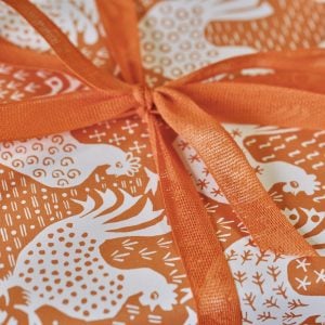 A parcel wrapped with Melon ribbon and Hens Cinnamon paper by Cambridge Imprint
