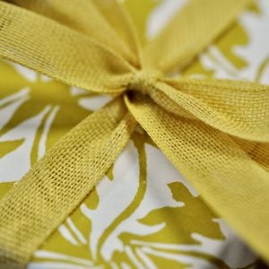 A parcel wrapped with Ochre ribbon and Dandelion Turmeric paper by Cambridge Imprint