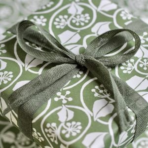 A parcel wrapped with Olive ribbon and SMall Ivy Stripe Sage Green paper by Cambridge Imprint