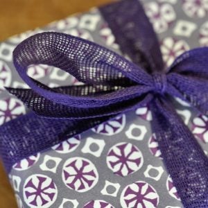 A parcel wrapped with Plum ribbon and Sea Urchin French Lavender by Cambridge Imprint