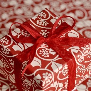 A parcel wrapped with Red ribbon and Small Ivy Stripe Red by Cambridge Imprint