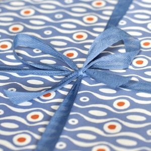 A parcel wrapped with Sea Blue ribbon and Persephone Cornflower paper by Cambridge Imprint